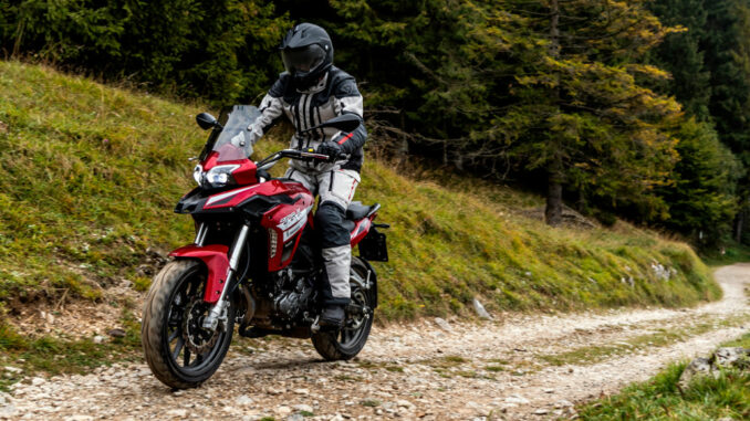 Eine rote Benelli TRK 502 fährt 2019 auf einem Waldweg.