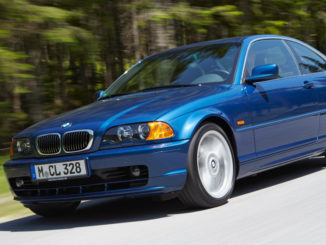 Ein blauer BMW 3er (E46 Coupé) fährt auf einer Landstraße am Waldrand.