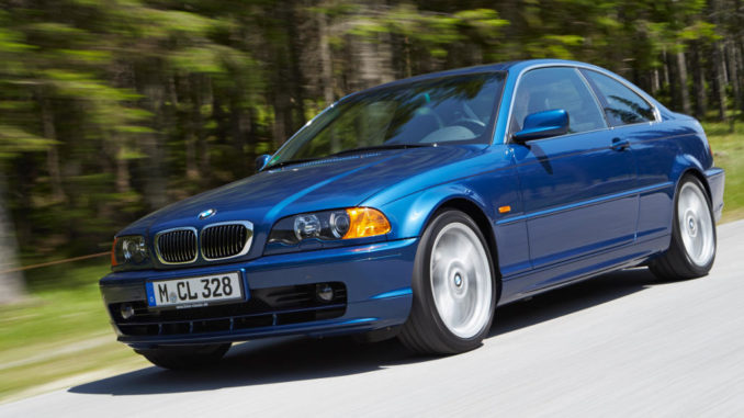 Ein blauer BMW 3er (E46 Coupé) fährt auf einer Landstraße am Waldrand.