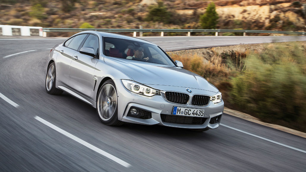 Ein silberner BMW 4er Gran Coupé mit M Sportpaket fährt 2014 auf einer Bergstraße.