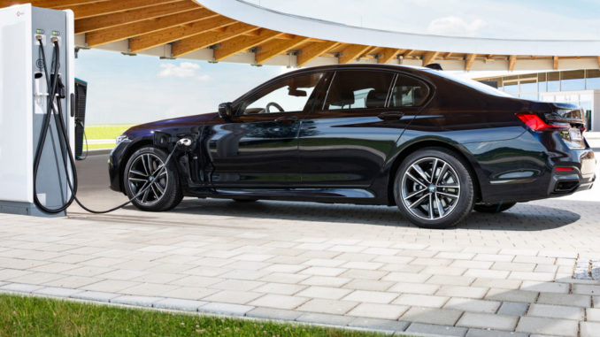 Ein blauer BMW 745e Plugin_hybrid steht 2020 an einer Ladesäule.