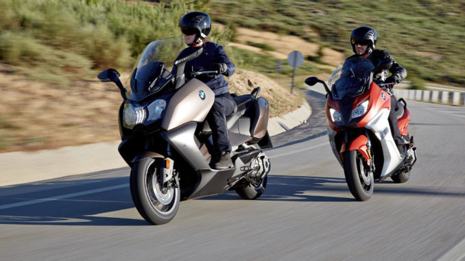 Eine rot-weiße BMW C 650 Sport und eine braun-graue BMW C650 GT fahren 2015 auf einer Bergstraße.