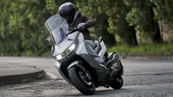 Der Fahrer einer silbernen BMW C 400 GT legt sich auf einer Landstraße in die Kurve.