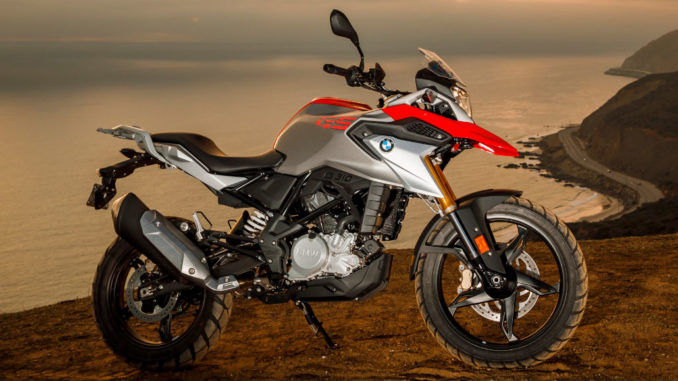 BMW Ein rot-silbernes BMW-Motorrad vom Typ G 310 GS (01/2017) steht vor einem Küstenpanorama bei Abenddämmerung.