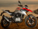 BMW Ein rot-silbernes BMW-Motorrad vom Typ G 310 GS (01/2017) steht vor einem Küstenpanorama bei Abenddämmerung.