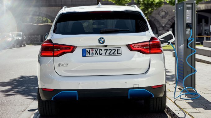 Ein weißer BMW iX3 steht im Sommer 2020 an einer Ladesäule in München.