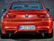 Das neue BMW M6 Coupé in Orange steht vor einer Betonwand (12/2014).