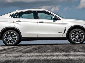 Ein weißer BMW X6 xDrive50i (F16 von 10/2014) aufgenommen im Profil steht auf einer Asphaltfläche mit Reifenspuren.