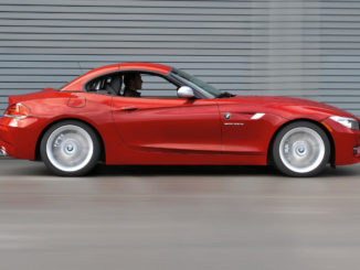 Ein roter BMW Z4 sDrive35is (11/2009) fährt dicht an einer Lärmschutzwand entlang.