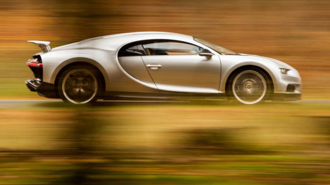 Ein silberner Bugatti Ciron fährt durch einen herbstlichen Wald.