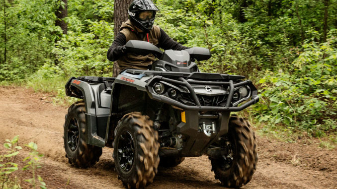 Ein ATV Can-Am Outlander fährt auf einem Waldweg.