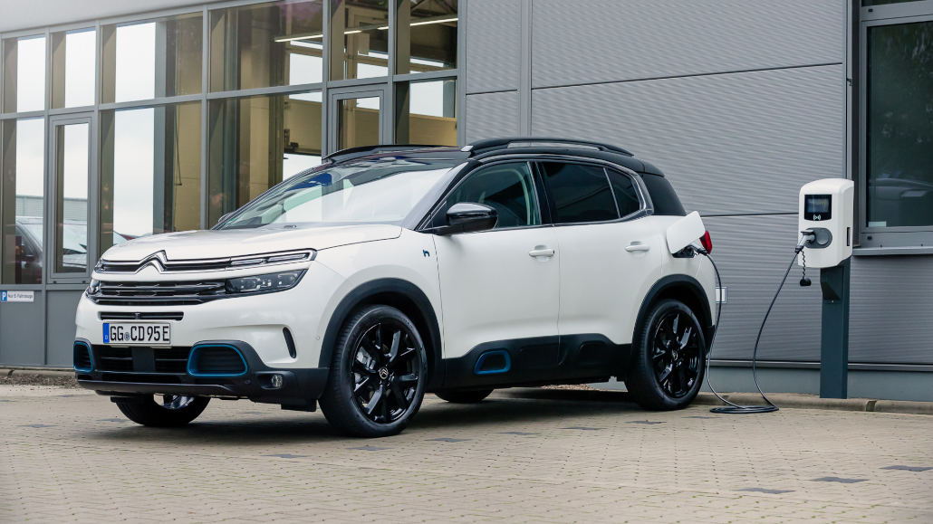 Ein weißer Citroen C5 Aircross Hybrid steht 2021 an einer Ladesäule.