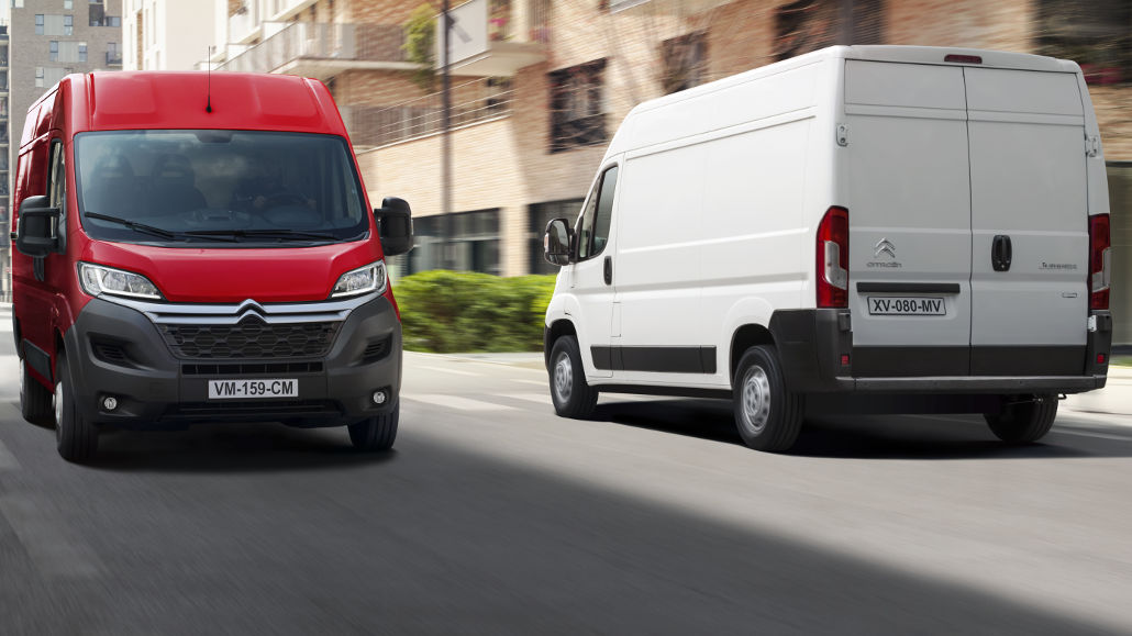 Ein weißer und ein roter Citroen Jumper fahren 2019 durch ein Wohnviertel.