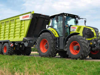 Straßentransport eines grünen Claas Axion 800 mit einem Häckseltransportwagen vom Typ Cargos 700.