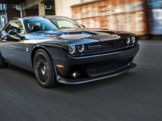 Ein schwarzer Dodge Challenger fährt auf einer Straße einer US-amerikanischen Stadt.