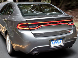 Ein grauer Dodge Dart fährt 2015 auf einer Landstraße durch den Wald.