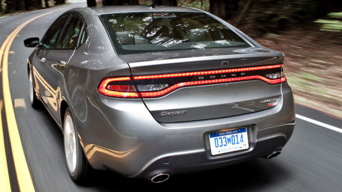 Ein grauer Dodge Dart fährt 2015 auf einer Landstraße durch den Wald.