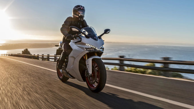 Eine weiße Ducati SuperSport fährt bei Sonnenaufgang auf einer Küstenstraße - PRESS TEST 2017