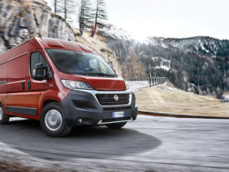 Kurvenfahrt eines roten Fiat Ducato auf einer Landstraße in den Bergen.