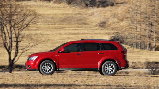 Ein roter Fiat Freemont fährt durch herbstliches Gelände.