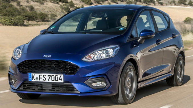 Ein blauer Ford Fiesta fährt 2017 auf einer sommerlichen Landstraße.