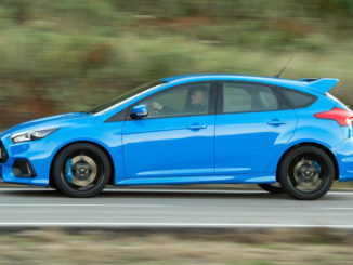 Ein blauer Ford Focus RS rast 2015 auf einer Landstraße entlang.