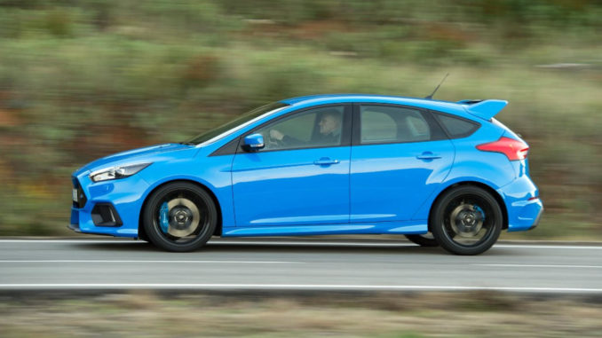 Ein blauer Ford Focus RS rast 2015 auf einer Landstraße entlang.