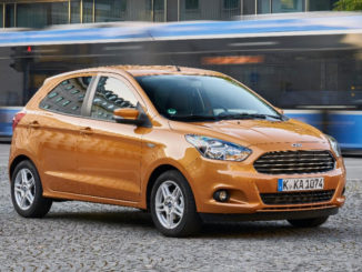 Ein bronze-farbener Ford Ka+ steht 2016 auf einem Platz in München, an dem eine Trambahn vorbeifährt.