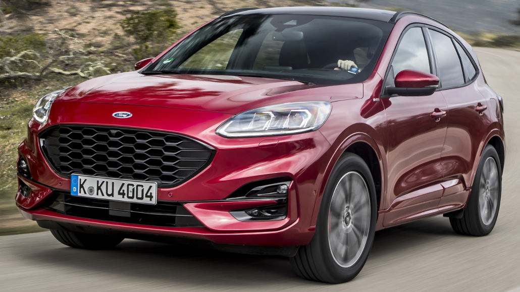 Ein roter Ford Kuga fährt 2020 auf einer Landstraße in den Bergen.