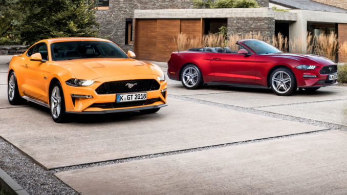 Ein oragenes Ford Mustang Coupé und ein rotes Cabrio stehen 2017 vor einer Villa.