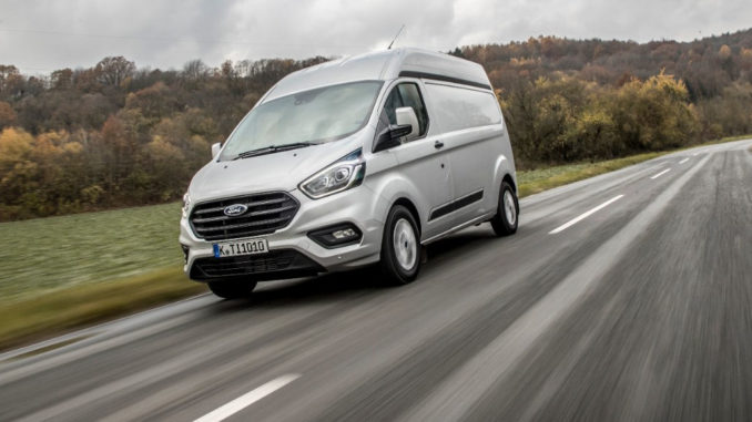 Ein silberner Ford Transit Custom fährt 2017 über eine Landstraße.