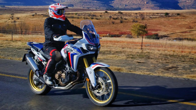 Eine Honda CRF1000 fährt auf einer Landstraße durch die Savanne.