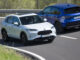 Ein weißer und blauer Honda ZR-V fahren 2023 auf einer Landstraße aneinander vorbei.