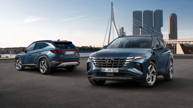 Zwei blaue Hyundai Tucson stehen 2020 vor einer Großstadtshilouette.