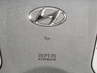 Lenkrad mit Hyundai-Logo, Hupen- und Airbag-Symbol in Großaufnahme.