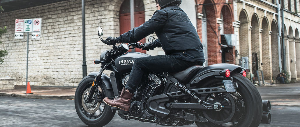 Eine schwarze Indian Scout Bobber des Modelljahres 2018 fährt durch eine amerikanische Innenstadt.