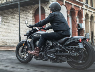 Eine schwarze Indian Scout Bobber des Modelljahres 2018 fährt durch eine amerikanische Innenstadt.