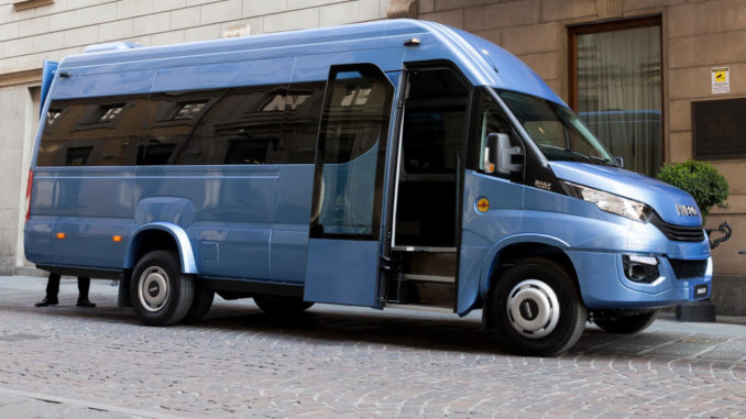 Ein blauer Iveco Daily Minibus steht vor einem Hotel.