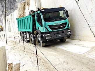 Ein türkiser Iveco Trakker fährt durch einen Steinbruch.