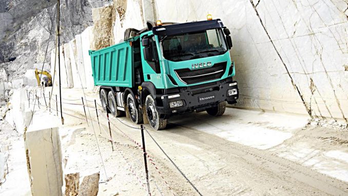 Ein türkiser Iveco Trakker fährt durch einen Steinbruch.