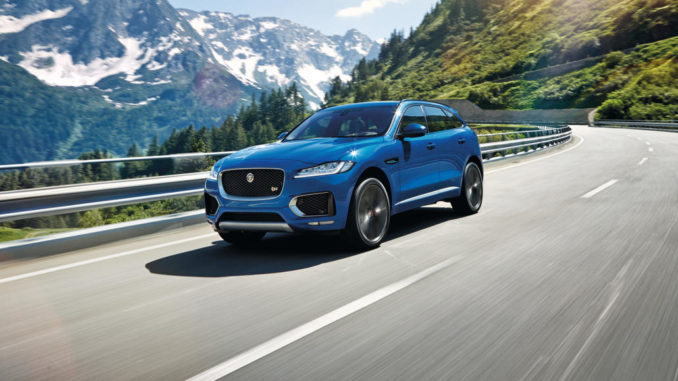 Ein blauer Jaguar F-Pace fährt durch eine Berglandschaft.