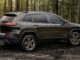 Ein brauner Jeep Cherokee 75th Anniversary steht 2016 auf einer Waldlichtung.