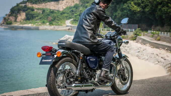 Eine blaue Kawasaki W800 steht 2021 vor einem Strand.