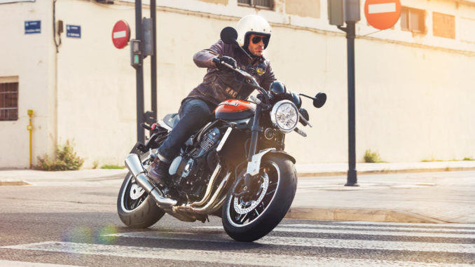 Eine rot-schwarze Kawasaki Z900RS überfährt einen Zebrastreifen.