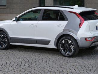 Ein weißer Kia Niro EV steht 2022 auf einer gepflasterten Fläche.