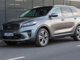 Ein grauer Kia Sorento des Modelljahres 2018 steht vor einem Bürogebäude.