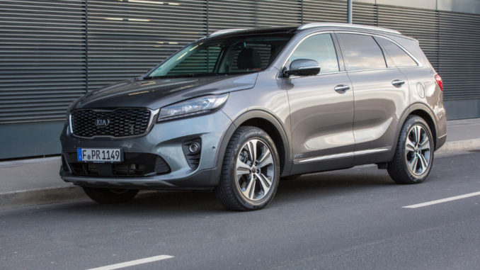 Ein grauer Kia Sorento des Modelljahres 2018 steht vor einem Bürogebäude.