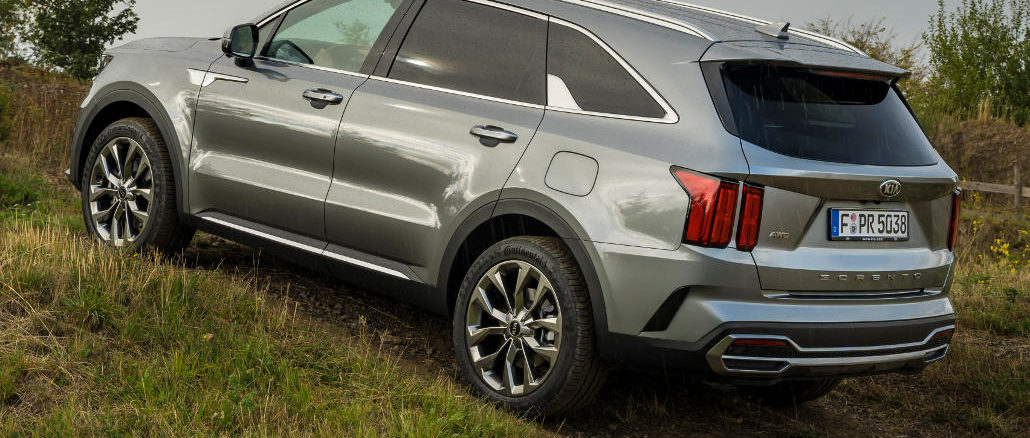 Ein grauer Kia Sorento des Modelljahres 2021 fährt auf einen Grashügel.
