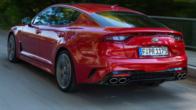 Ein roter Kia Stinger fährt 2018 durch einen Wald.