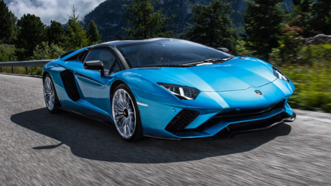 Ein blauer Lamborghini Aventador S Roadster fährt mit geschlossenem Dach auf einer Bergstraße.